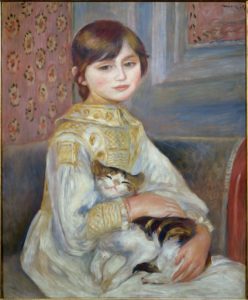 Une jeune fille nous regarde, le visage de face, le corps de trois-quart, assise dans un intérieur avec un chat sur ses genoux. 